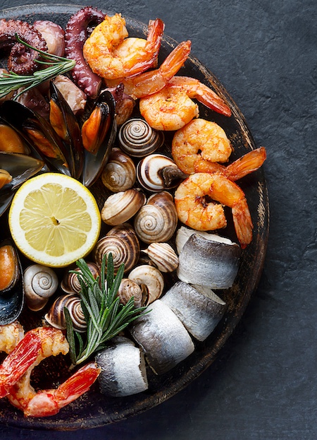 Seafood charcuterie platter board with shrimp, oysters, fish and octopus on black background. Top view, close up